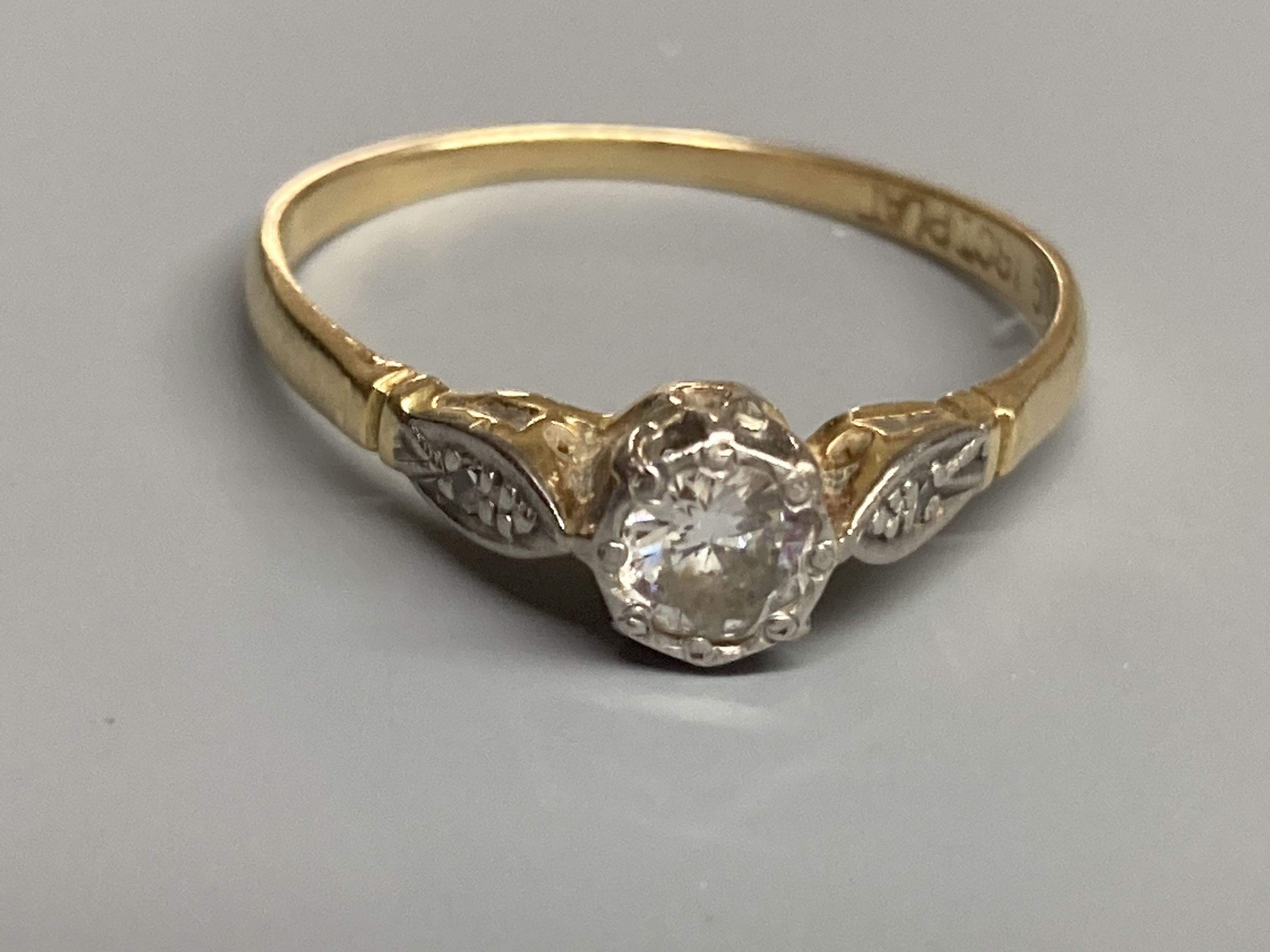 An 18ct & plat, single stone diamond ring, with diamond set shoulders, size P, gross 1.9 grams.
